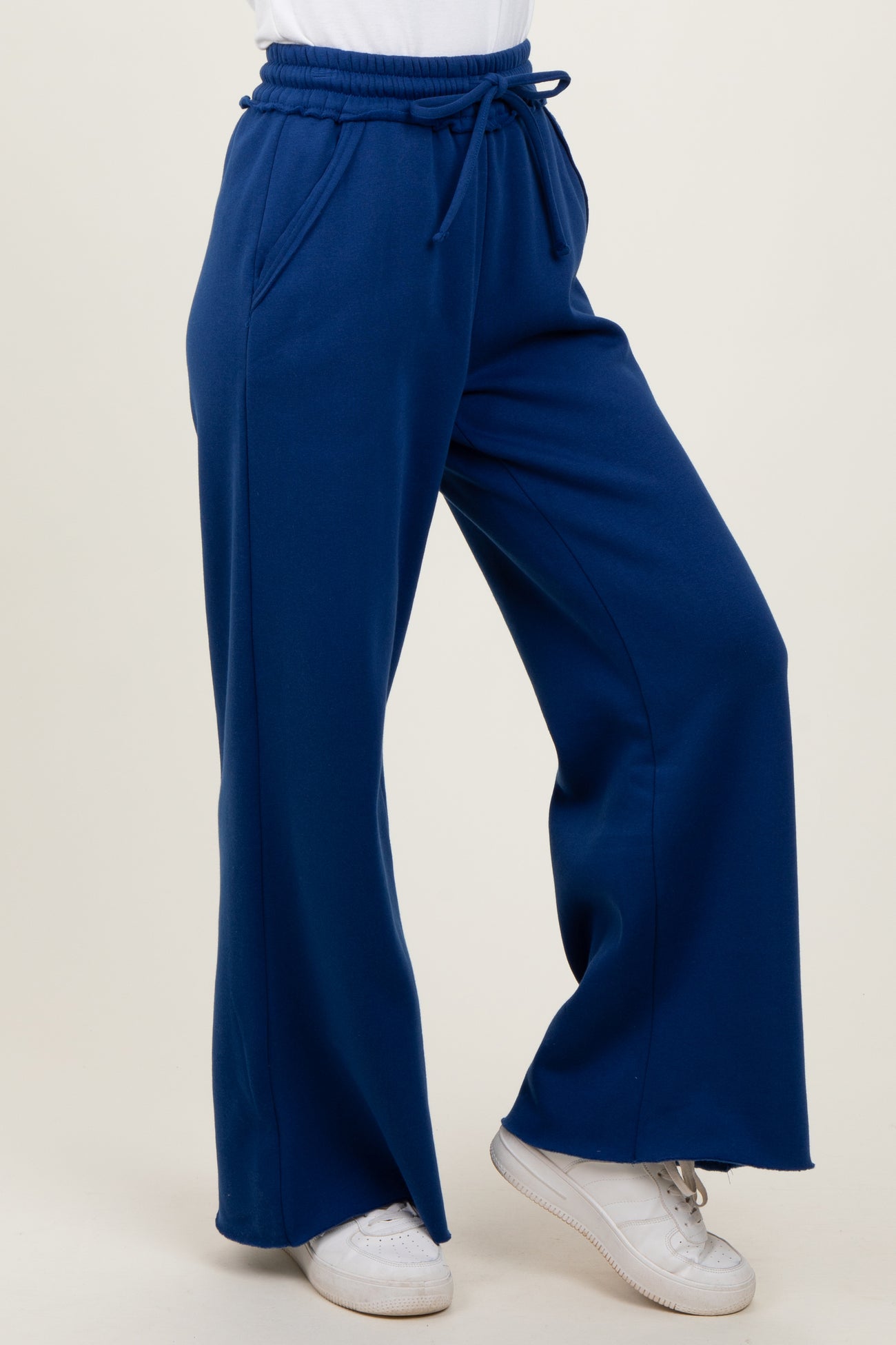 woman wearing high-waisted navy blue wide-leg pants with pockets and a drawstring waistband