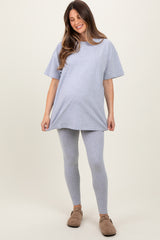 woman wearing a gray oversized t-shirt and gray leggings, showing her baby bump in maternity wear