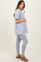 woman wearing a gray oversized maternity t-shirt and gray leggings, holding her baby bump