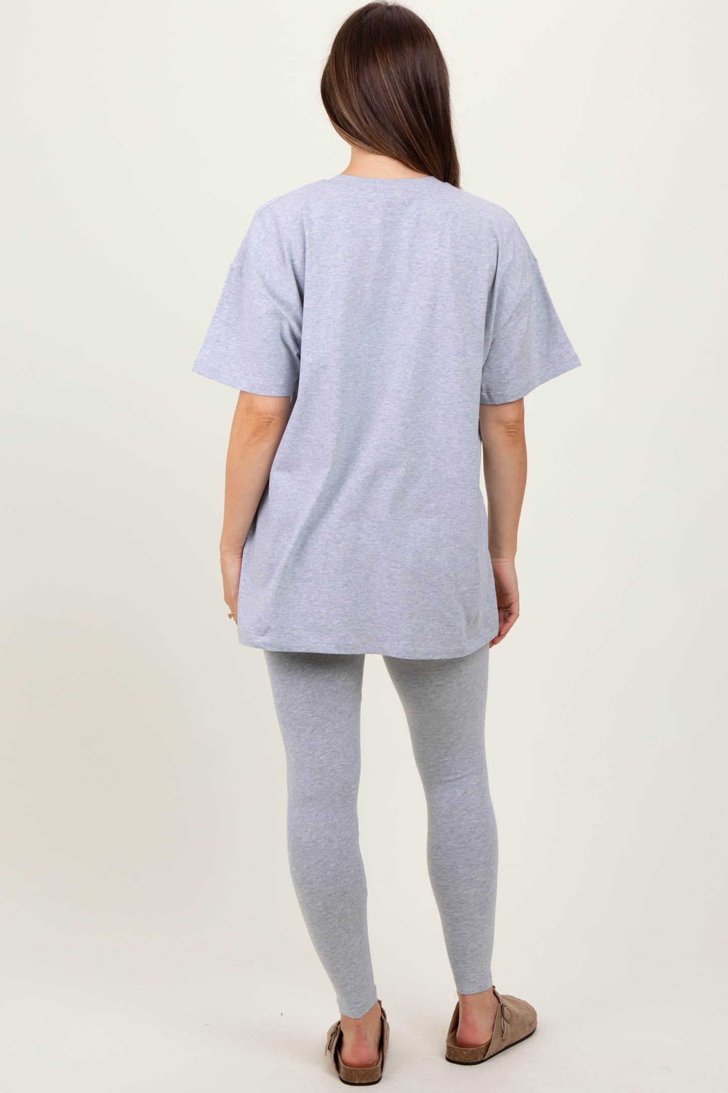 woman wearing a light gray oversized maternity t-shirt and matching leggings, showing a relaxed fit from the back