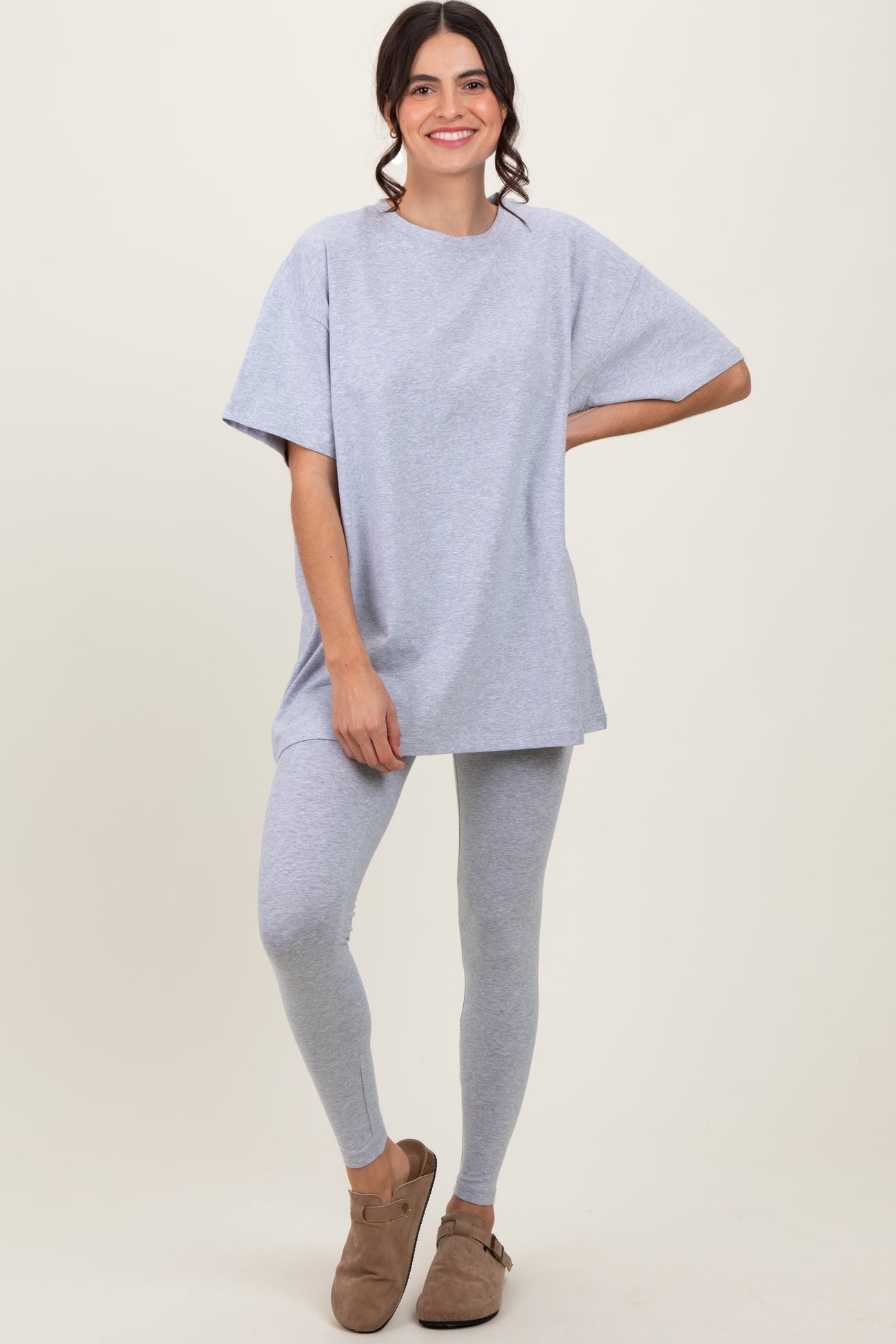 woman wearing a gray oversized t-shirt and matching leggings, styled with casual slip-on shoes