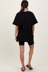 woman wearing an oversized black t-shirt with short sleeves and black biker shorts, facing away from the camera