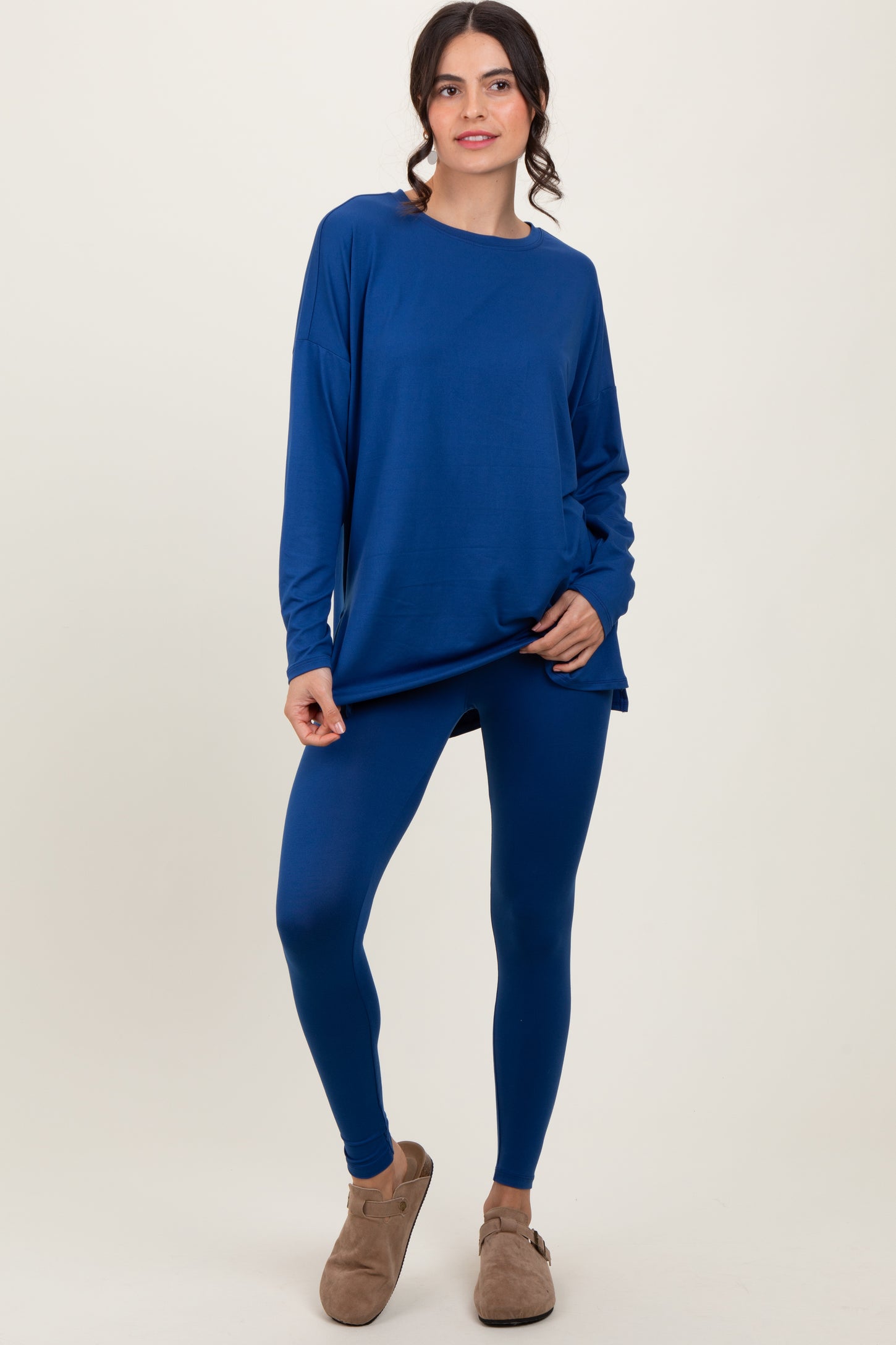 woman wearing a deep blue long sleeve top and matching leggings, paired with cozy slippers