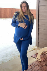 woman wearing a navy blue maternity top and leggings, holding her baby bump outside