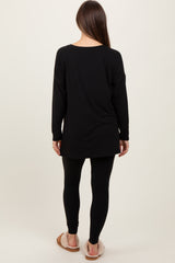 woman wearing a black long sleeve maternity tunic with black leggings and slippers, viewed from the back