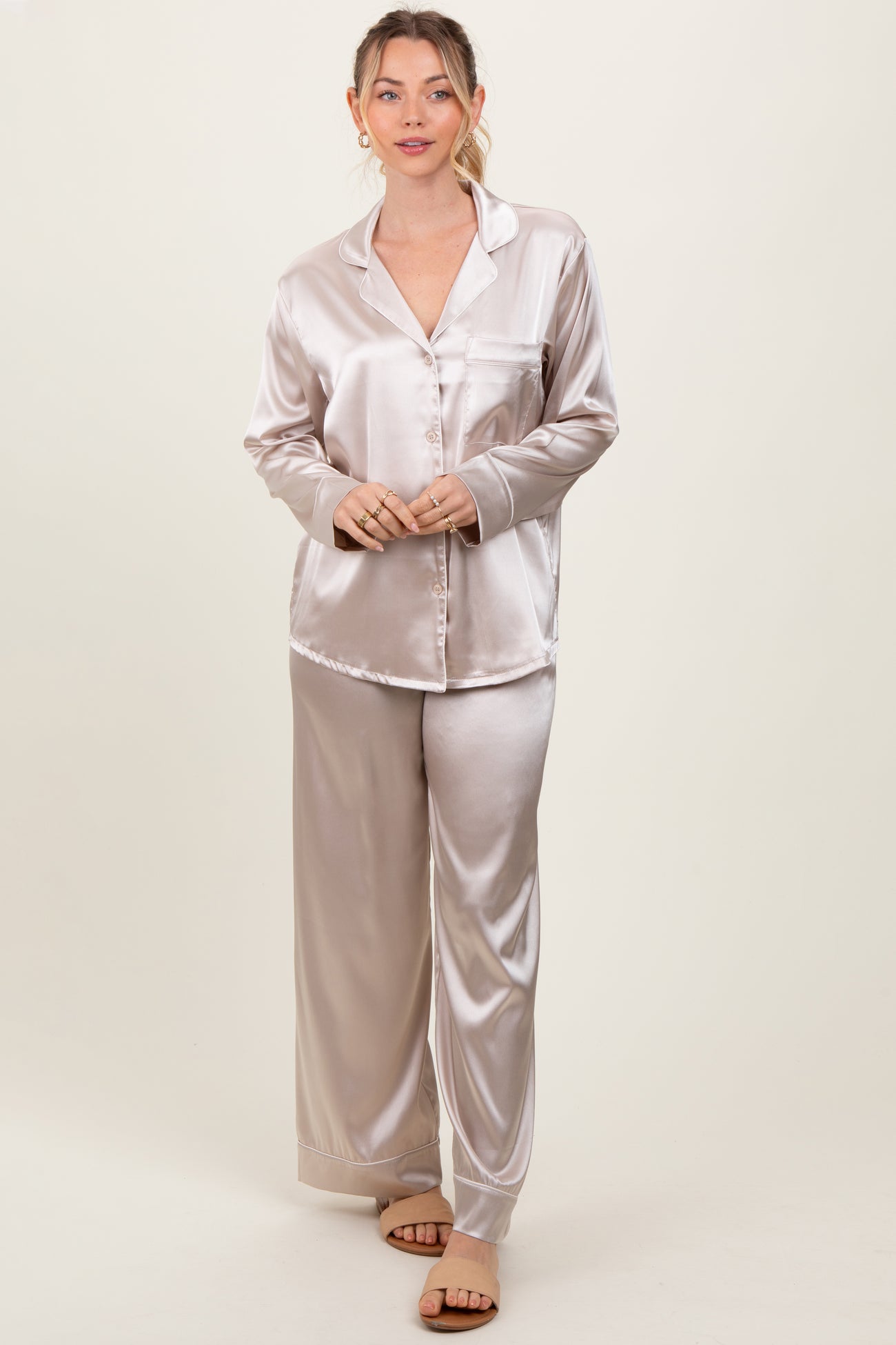 woman wearing a light beige satin pajama set with a button-up top and wide-leg pants
