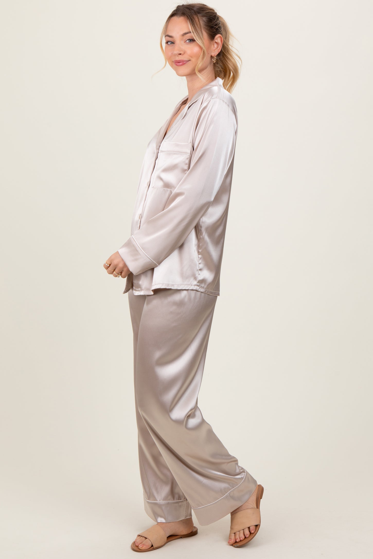woman wearing a light beige satin pajama set with long sleeves and loose-fitting pants