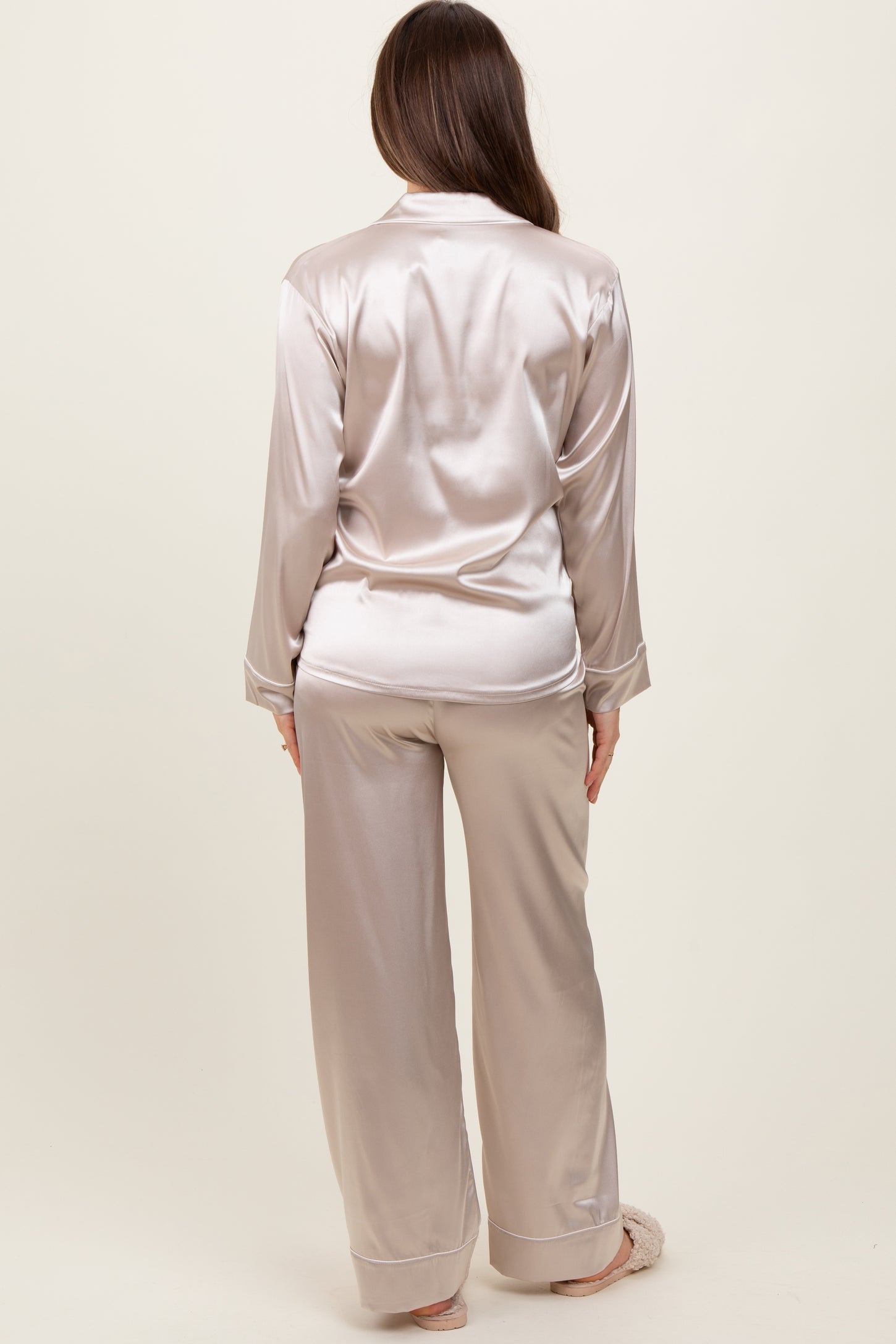 woman wearing a light beige satin maternity pajama set, featuring a long sleeve button-up top and wide-leg pants