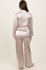 woman wearing a light beige satin maternity pajama set, featuring a long sleeve button-up top and wide-leg pants