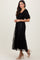 woman wearing a black puff sleeve maxi dress with floral embroidery and tiered skirt, paired with nude high heels