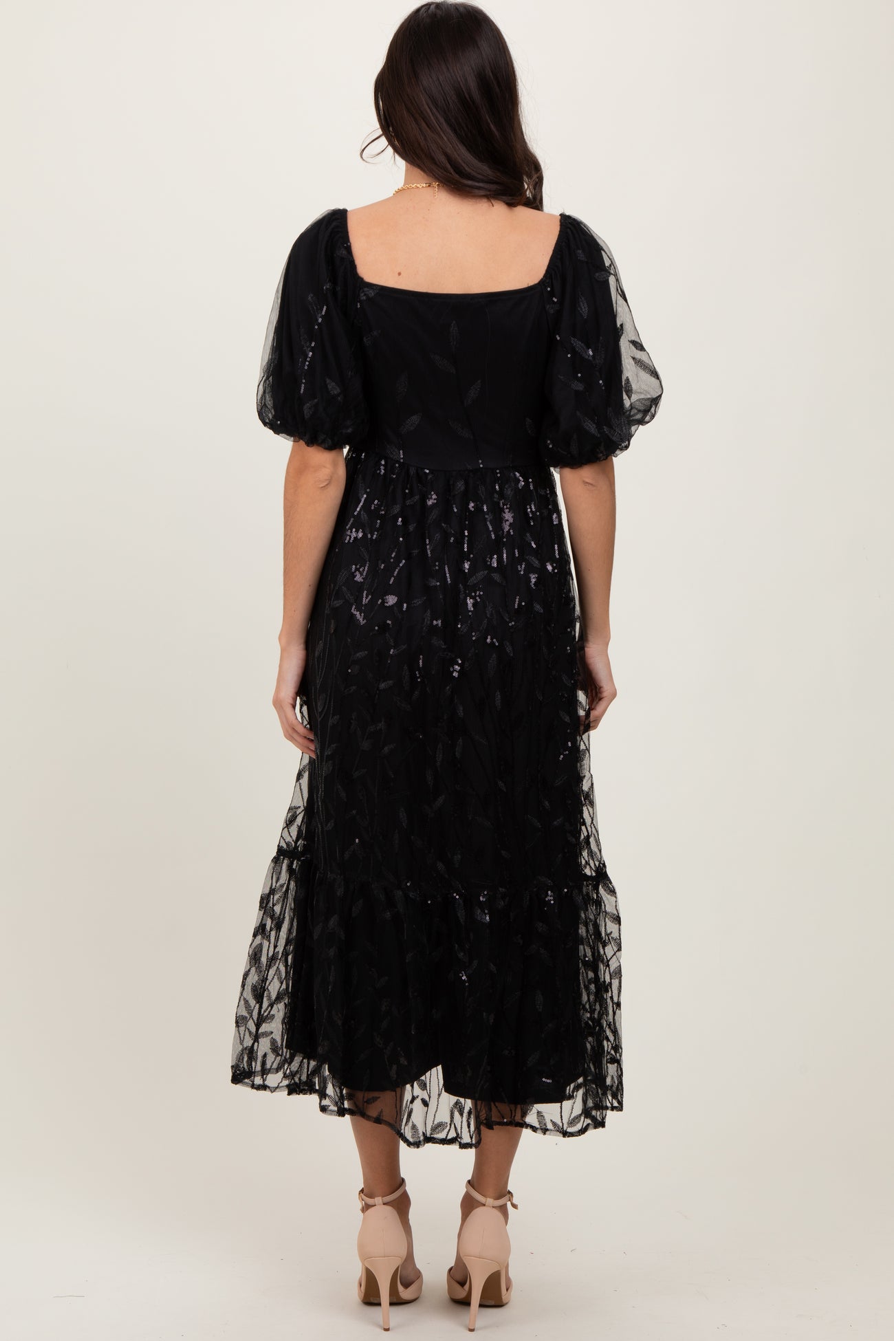 woman wearing a black puff sleeve maxi dress with a layered tulle skirt, shown from the back