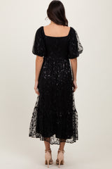 woman wearing a black puff sleeve maxi dress with a layered tulle skirt, shown from the back