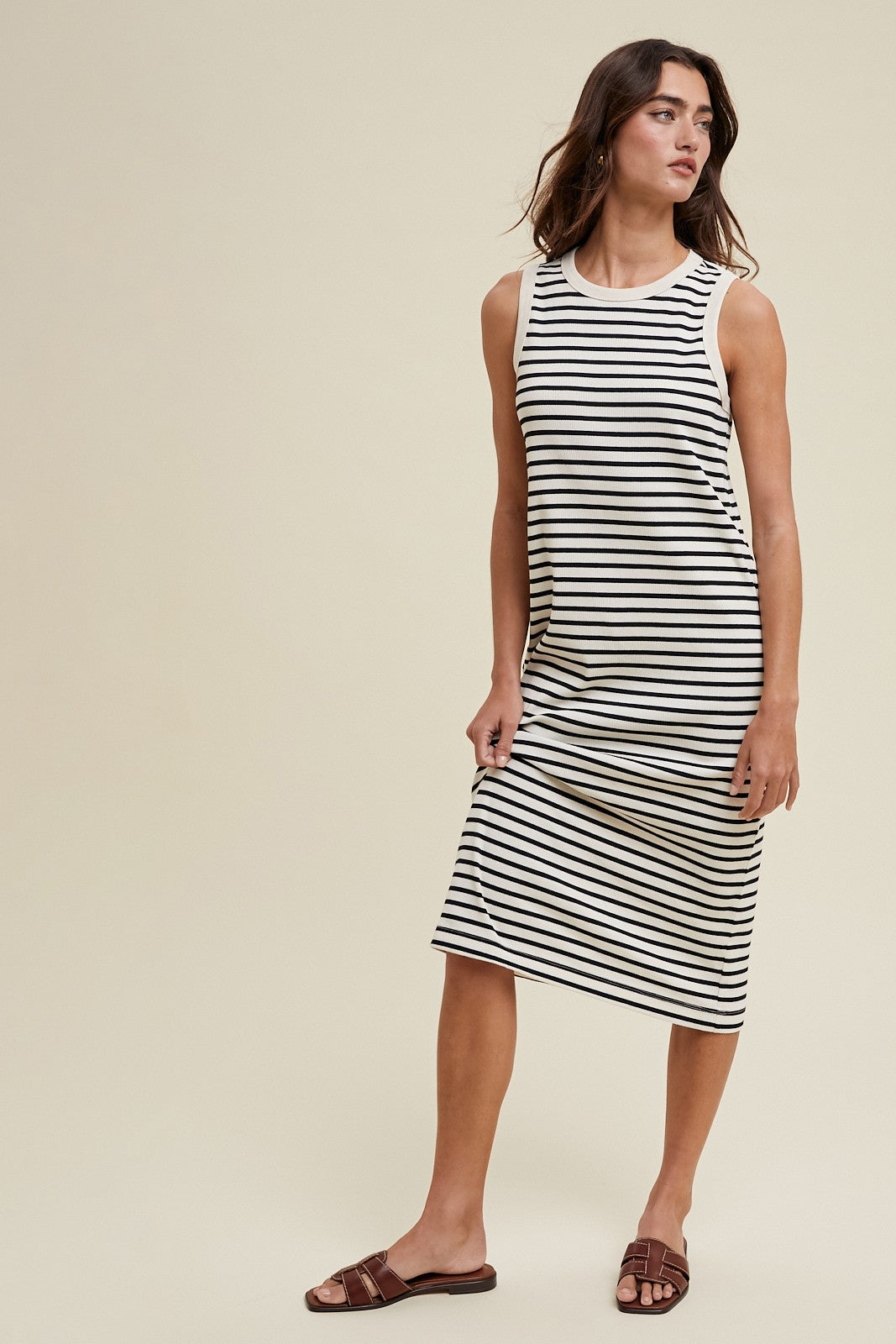 woman wearing a black and white striped sleeveless midi dress with a relaxed fit