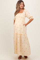 woman wearing a floral printed yellow maternity maxi dress with puff sleeves and pockets, showcasing her baby bump