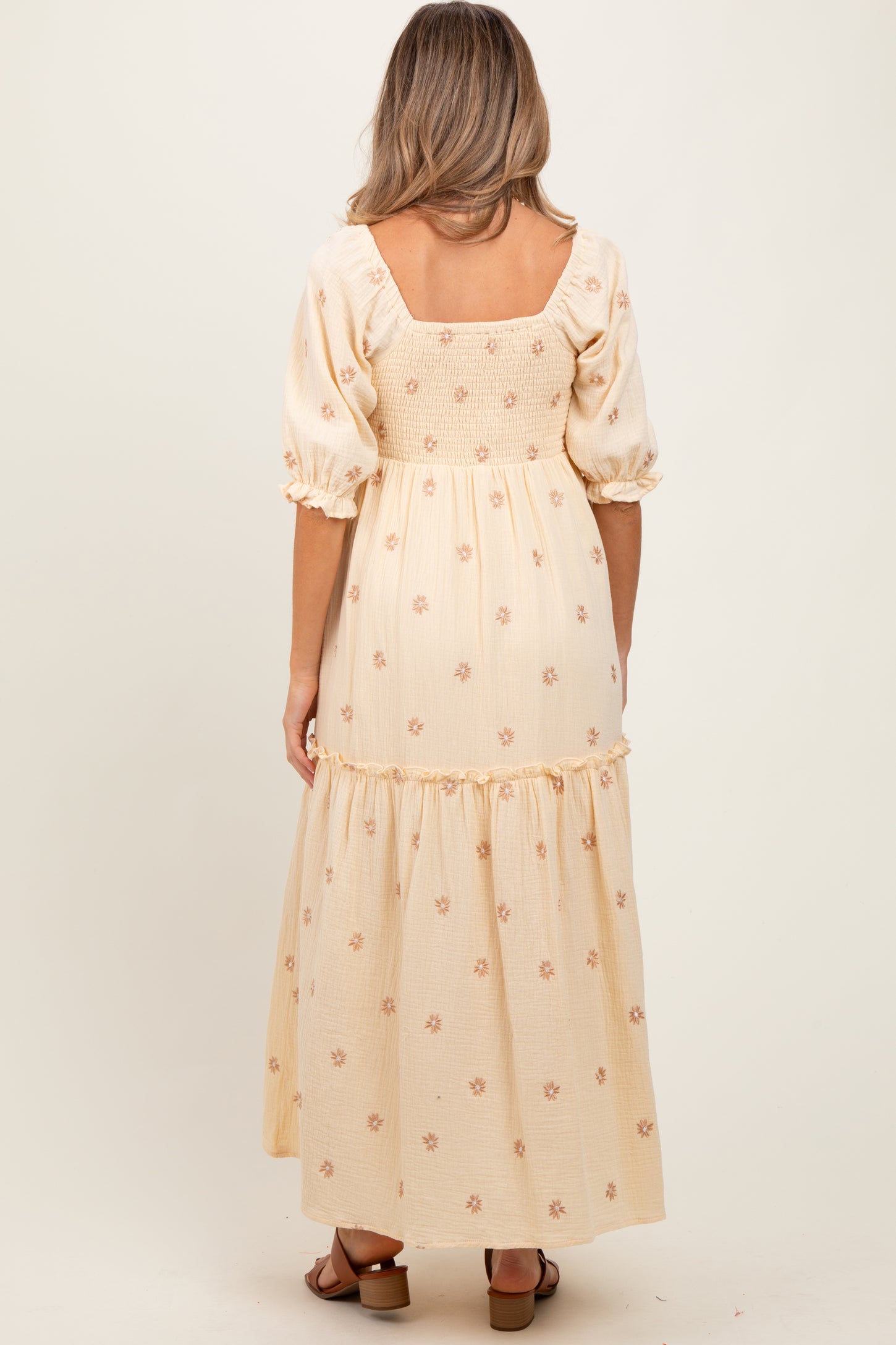 woman wearing a maternity wear yellow floral maxi dress with puff sleeves and a smocked back, showing a baby bump