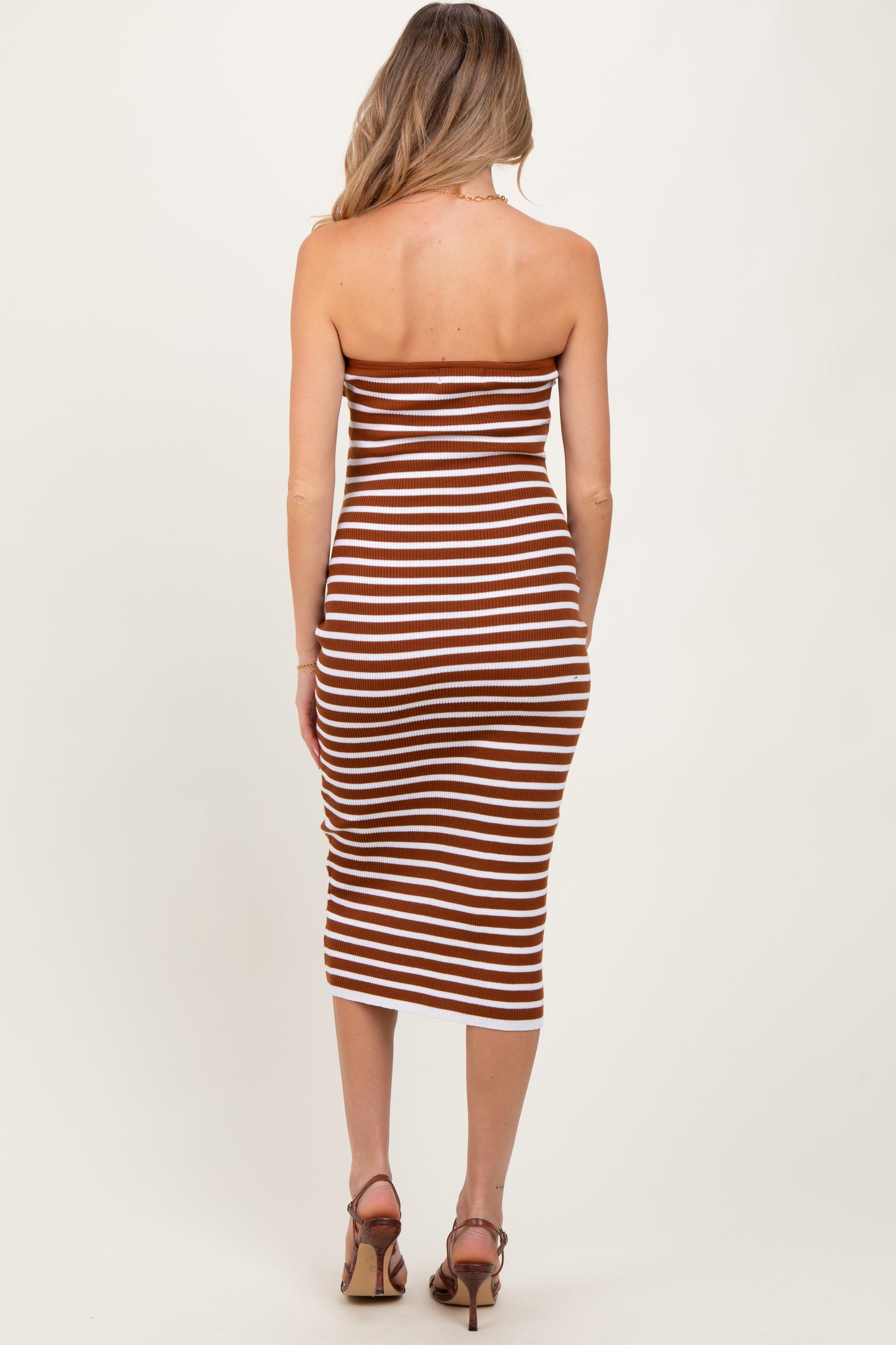 woman wearing a brown and white striped midi strapless maternity dress, showing a side view of the back