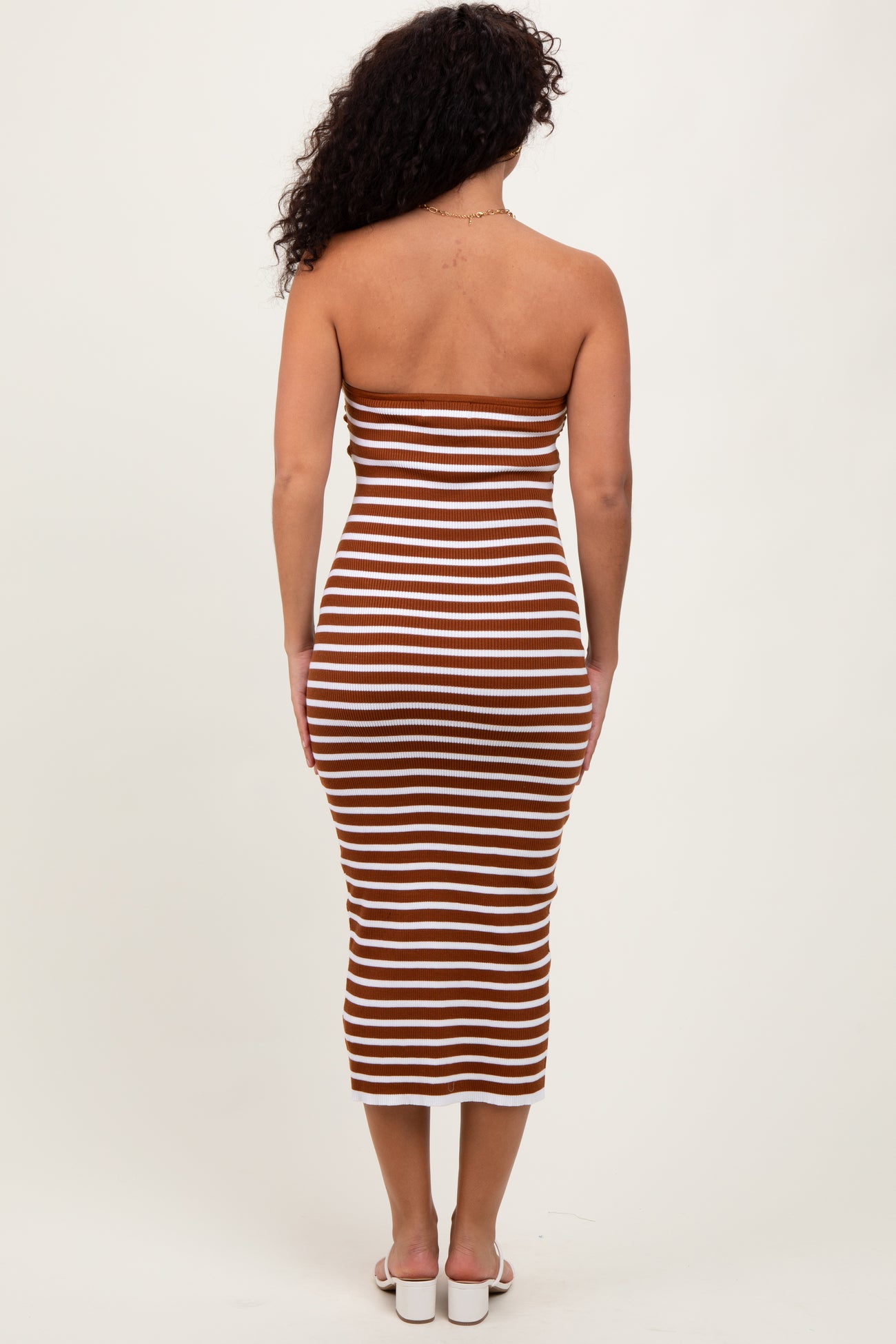 woman wearing a brown and white striped midi dress with a fitted silhouette and strapless design from the back