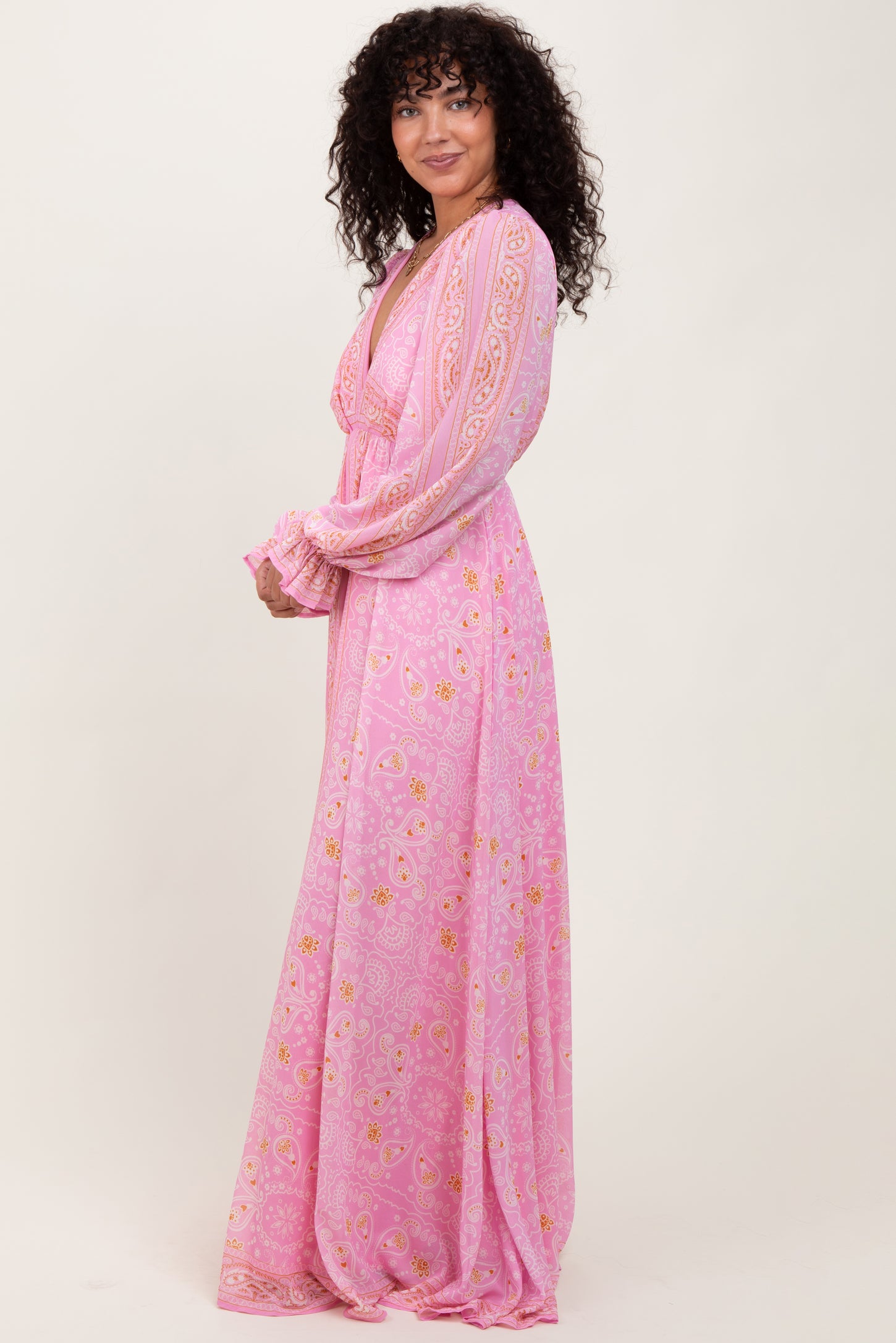 woman wearing a pink long sleeve maxi dress with floral prints and a tie neckline