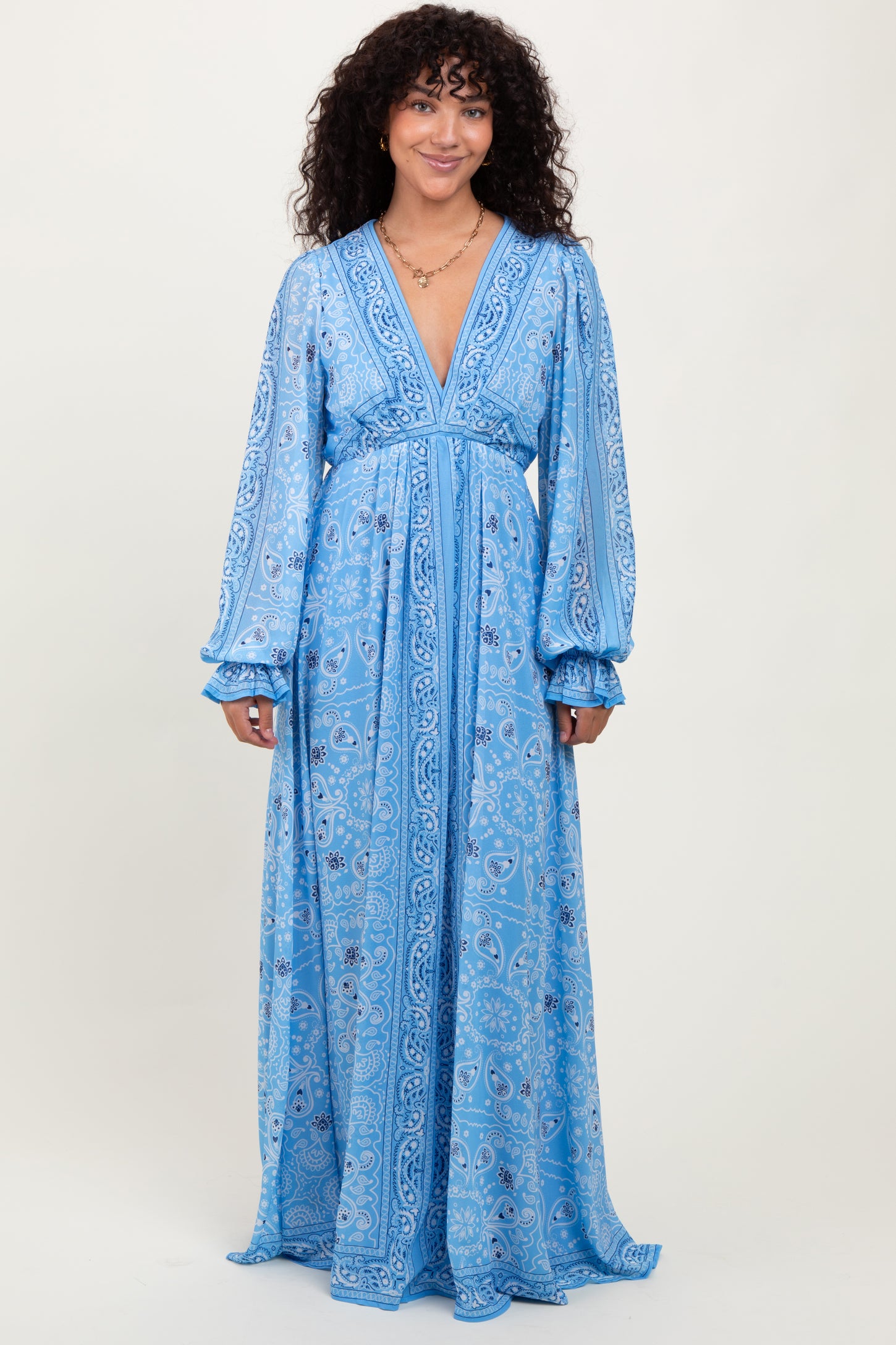 woman wearing a long blue paisley maxi dress with long sleeves and a deep V-neckline