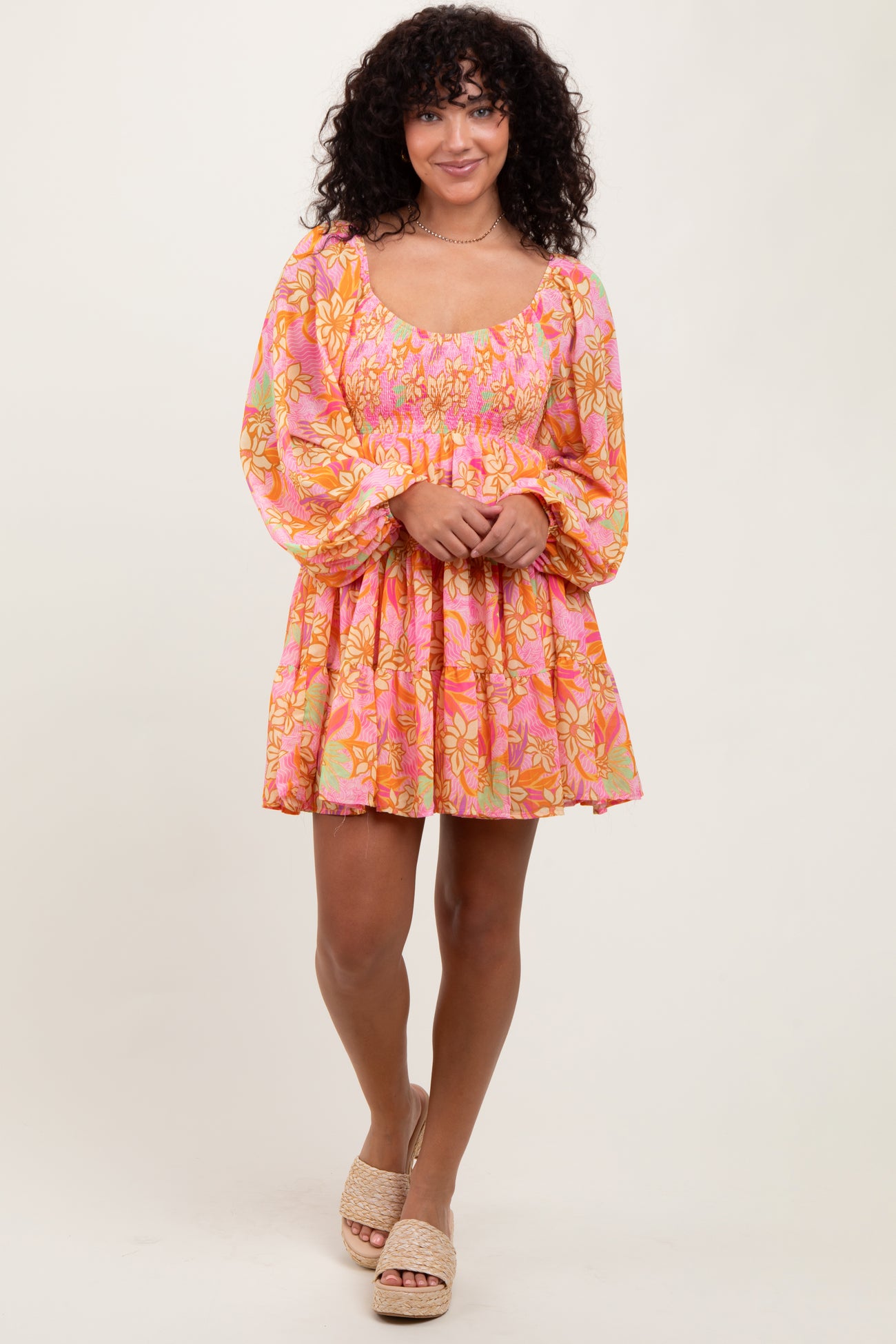 woman wearing a pink floral smocked mini dress with long puff sleeves and a flared skirt