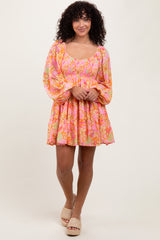 woman wearing a pink floral smocked mini dress with long puff sleeves and a flared skirt