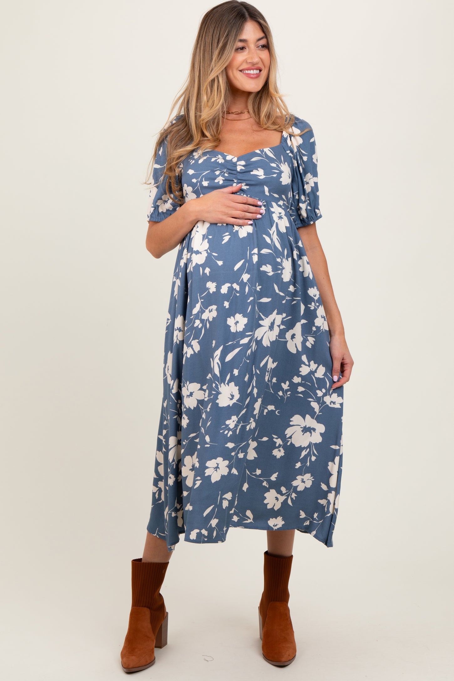 woman wearing a blue floral maternity dress with short sleeves and a baby bump visible