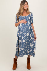 woman wearing a blue floral maternity dress with short sleeves and a baby bump visible