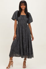woman wearing a dark gray floral midi dress with puff sleeves and a smocked bodice