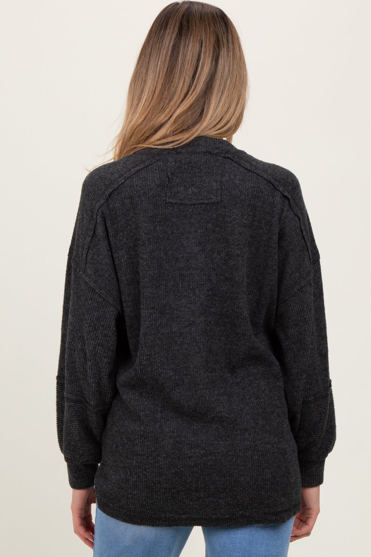 woman wearing a dark gray oversized maternity sweater, showing the back view with dropped shoulders and relaxed fit