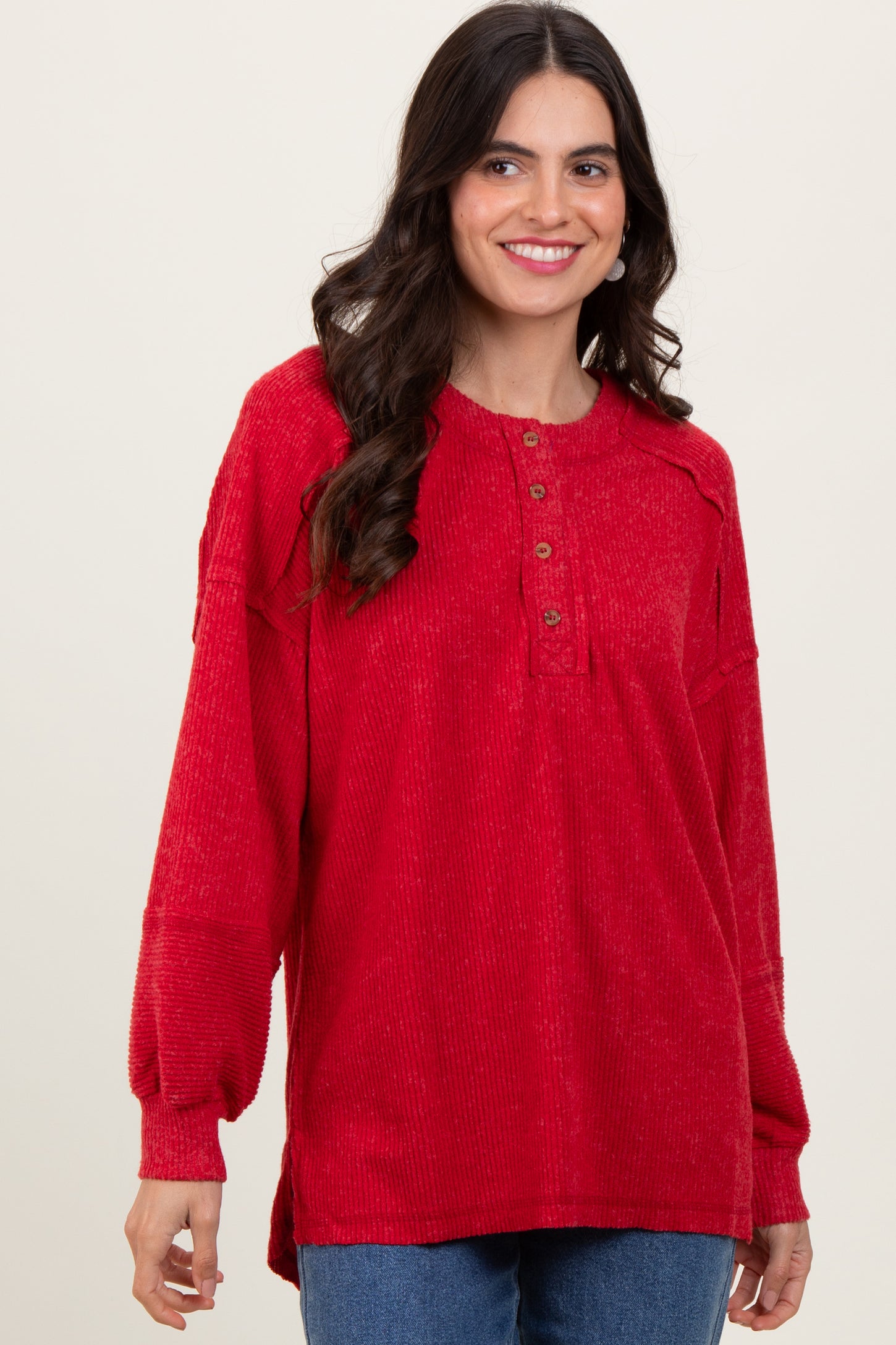 woman wearing a red long sleeve pullover top with buttons and loose fit, smiling at the camera