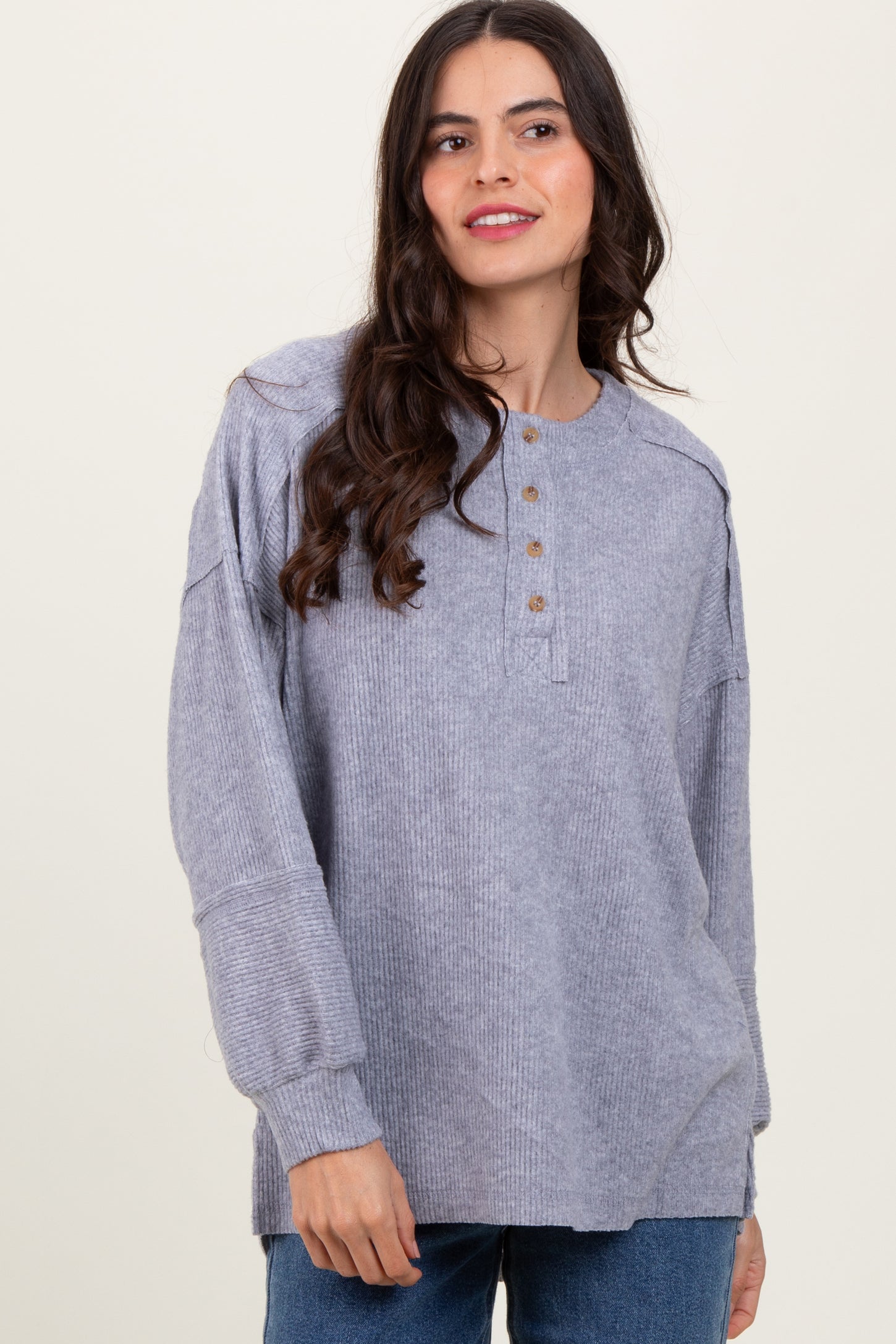 woman wearing a gray ribbed long sleeve henley top with button detail and relaxed fit