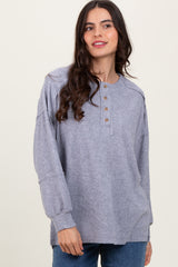woman wearing a gray ribbed long sleeve henley top with button detail and relaxed fit