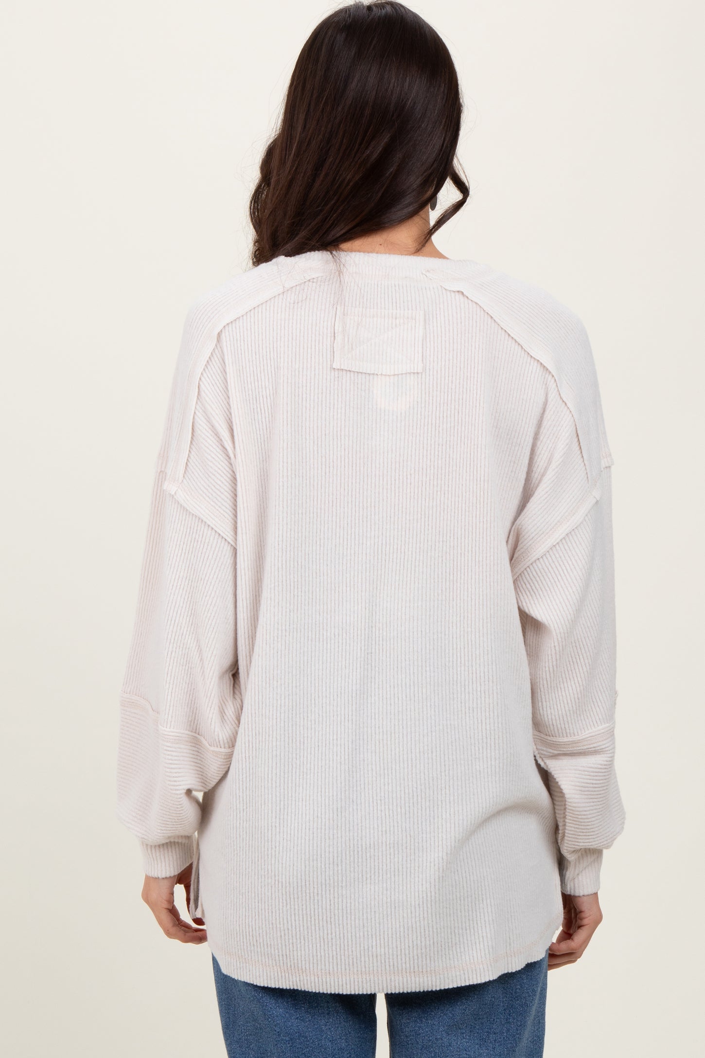woman wearing a light beige oversized sweater with a relaxed fit and dropped shoulder seams