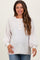 woman wearing a light beige maternity long sleeve top with buttons, showcasing her baby bump