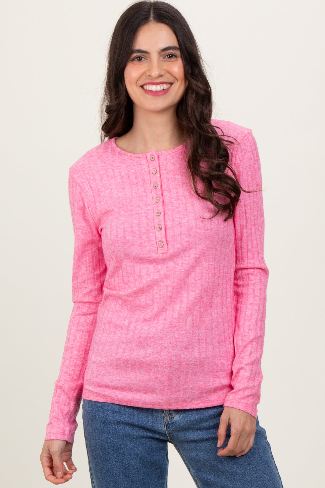 woman wearing a pink long sleeve button-up ribbed top with a round neckline and relaxed fit