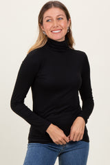 woman wearing a black long sleeve turtleneck top with a slim fit and smiling