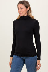 woman wearing a black long sleeve turtleneck top with fitted styling and paired with blue jeans