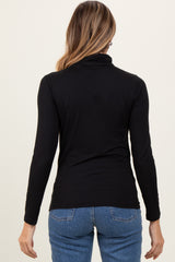 woman wearing a black long sleeve turtle neck top with a fitted style and back view, paired with blue jeans