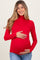 woman wearing a red long sleeve maternity top and holding her baby bump