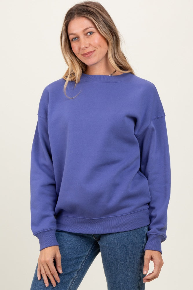 woman wearing a purple oversized sweatshirt with a crew neck and relaxed fit, paired with blue jeans