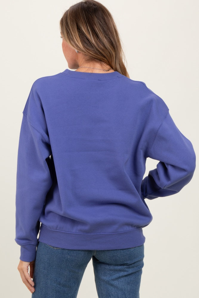 woman wearing a purple oversized crewneck sweatshirt, facing away, styled with relaxed fit denim jeans