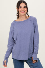 woman wearing a purple long sleeve top with a boat neckline and relaxed fit, smiling at the camera