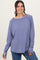woman wearing a purple long sleeve top with a boat neckline and relaxed fit, smiling at the camera
