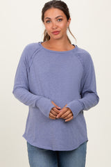 woman wearing a purple long sleeve maternity top with a scoop neckline and curved hem, gently holding her baby bump
