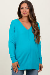 woman wearing a turquoise v-neck maternity sweater with a relaxed fit and side slits, showcasing her baby bump