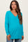 woman wearing a turquoise v-neck maternity sweater with a relaxed fit and side slits, showcasing her baby bump