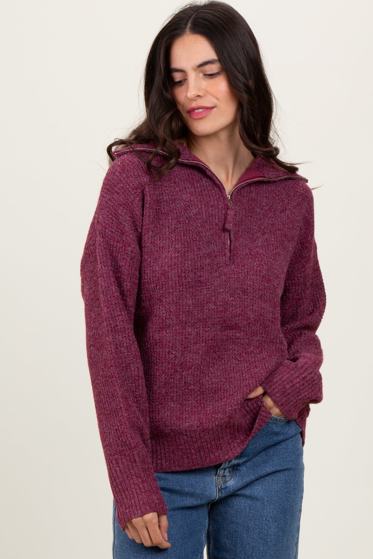 woman wearing a maroon zip-up sweater with a textured finish and relaxed fit, paired with blue jeans