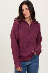 woman wearing a maroon zip-up sweater with a textured finish and relaxed fit, paired with blue jeans
