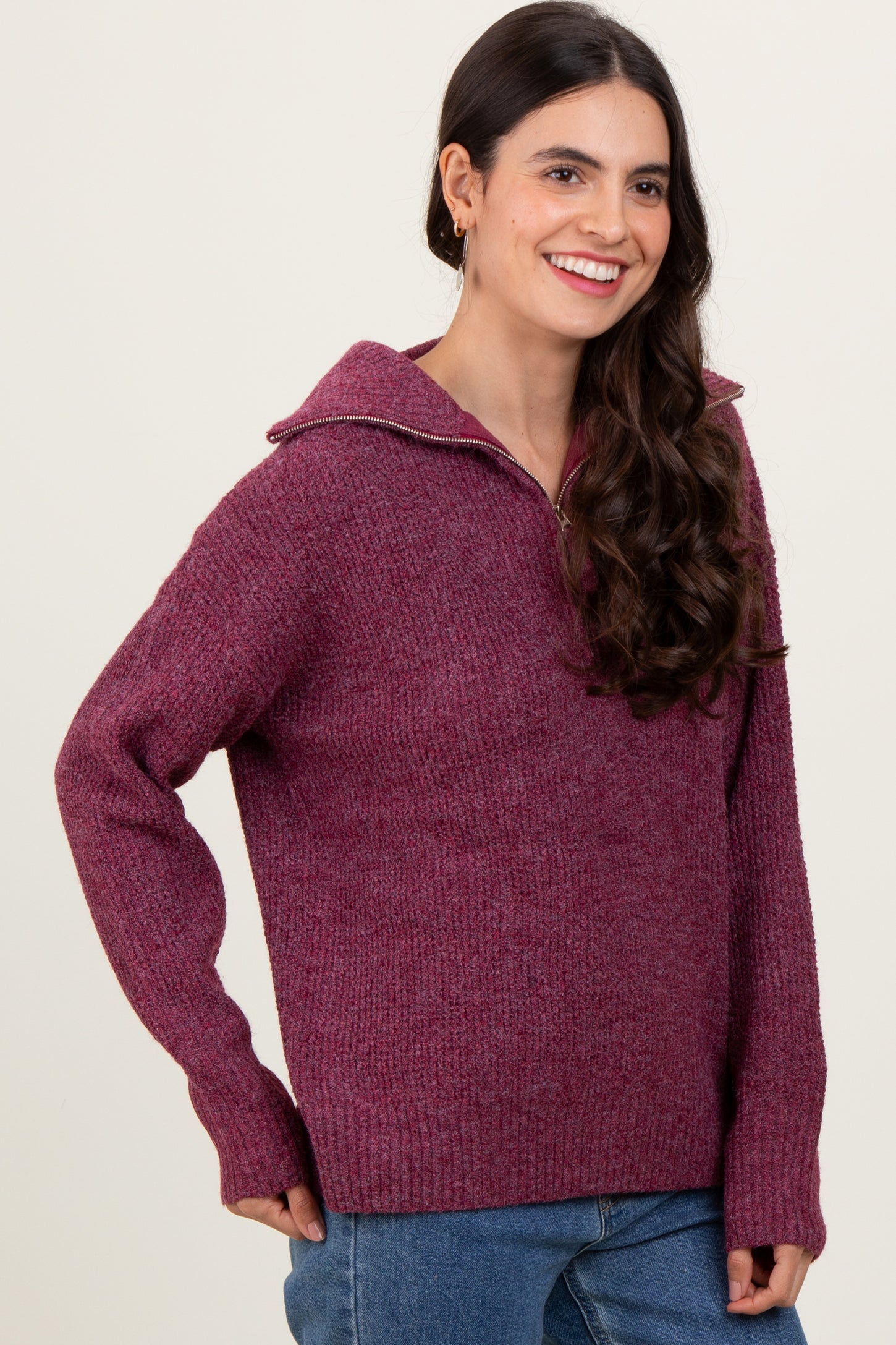 woman wearing a burgundy oversized sweater with a zip-up collar and long sleeves