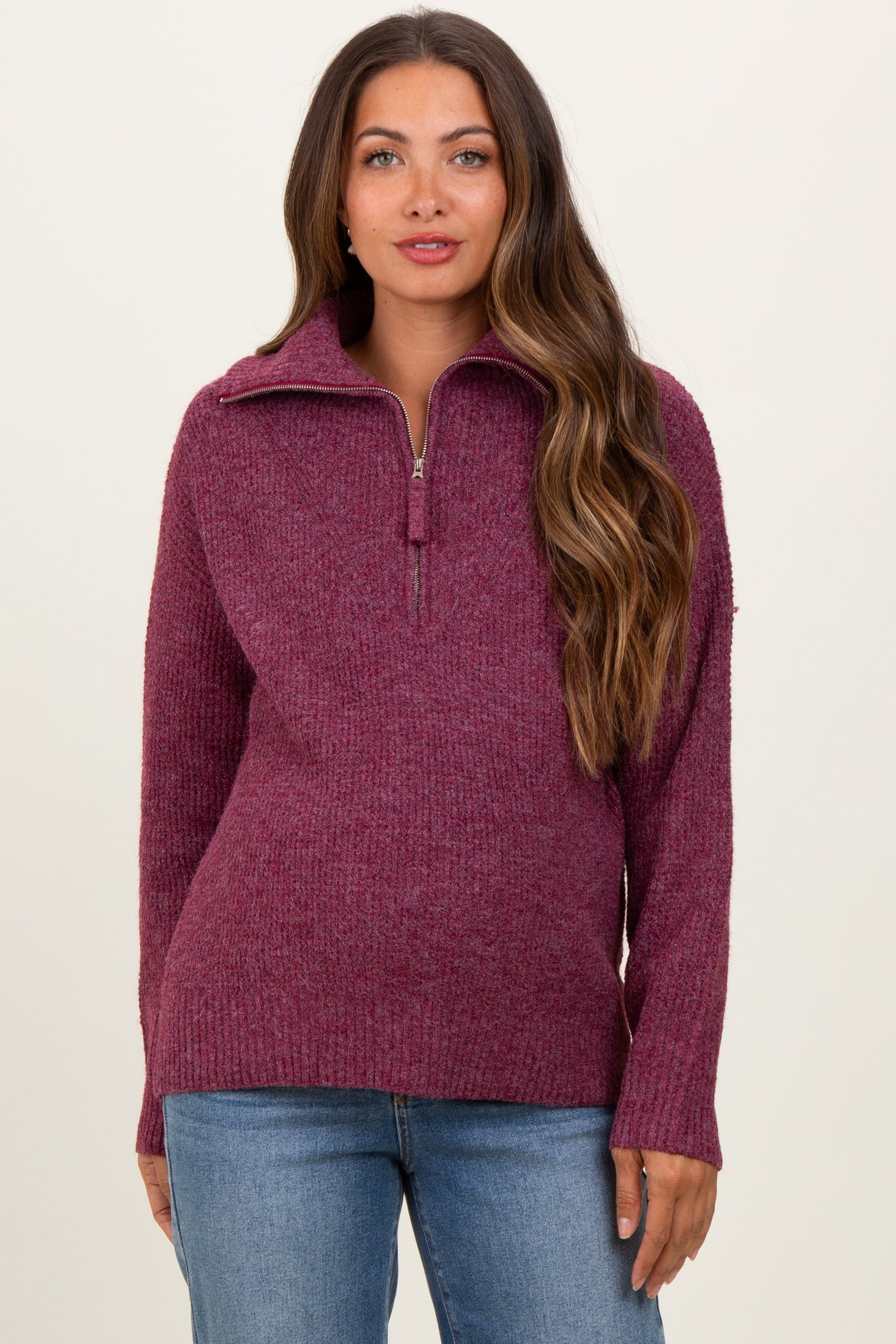 woman wearing a burgundy zip-up maternity sweater with a cozy knit texture and a relaxed fit
